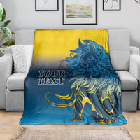 Lion print blanket in blue and yellow, spread over a couch with oversized lion graphic