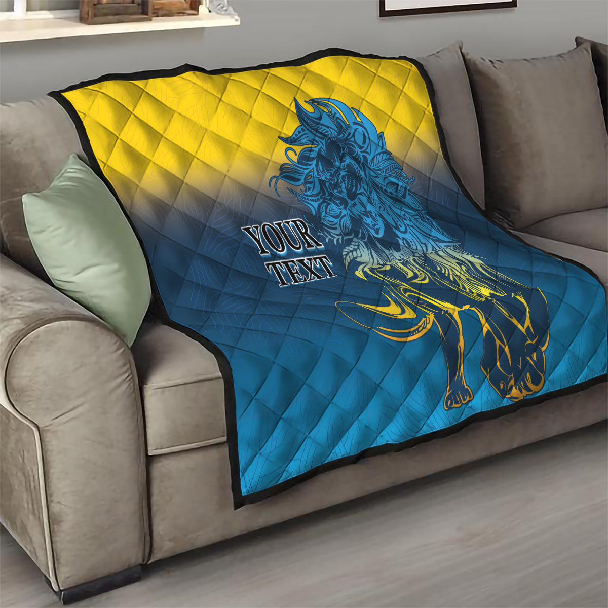 Folded quilt blanket on a couch with blue-and-yellow diamond quilting and blue lion, “YOUR TEXT”