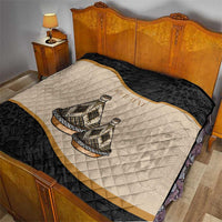 Black and beige quilt with diagonal stripes and tribal pottery pattern, fully spread on bed