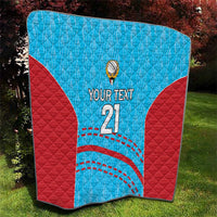 Blue and red cricket quilt with 'YOUR TEXT 21' text, ball emblem, and arc stitches.
