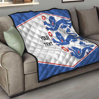 Blue and white quilt blanket with lion emblems and red border on sofa