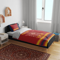 Red and navy bedding set with crest and yellow diamond trim on a wooden bed