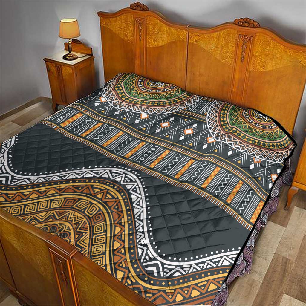 Ethnic bed quilt with black, gold, green and orange patterned design, quilted surface