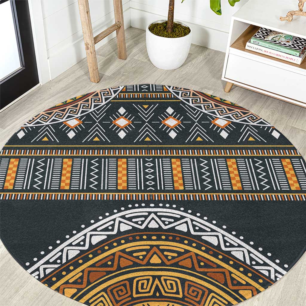 Round area rug with charcoal base and orange, gold, and white geometric tribal pattern