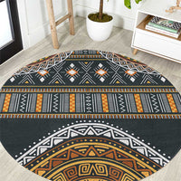 Round area rug with charcoal base and orange, gold, and white geometric tribal pattern
