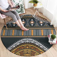 Round tribal-style rug, charcoal with bold bands, diamonds, and orange-gold accents