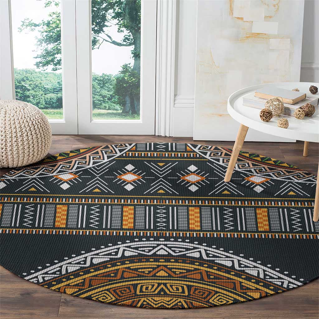 Round black rug with aztec-inspired motifs, orange and gold detailing, and white outlines