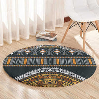 Round patterned carpet with charcoal background, orange-gold bands, and white tribal shapes
