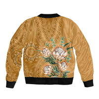 Gold unisex bomber jacket with black collar and cuffs, back paisley pattern with protea bouquet