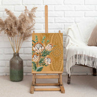 Gold protea canvas wall art standing on wooden easel with green leaves and patterns