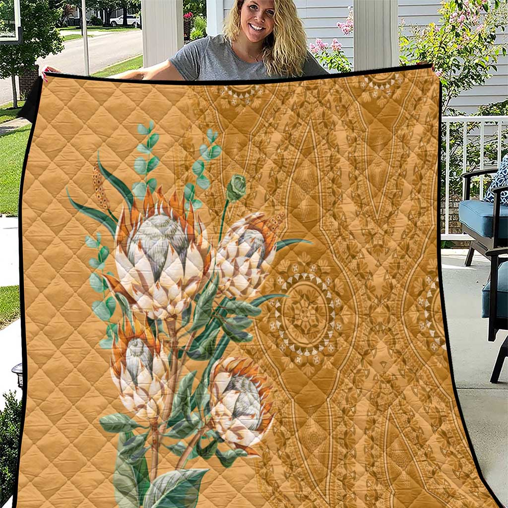 Gold quilt with diamond stitching and teal floral protea motif, black trim edge