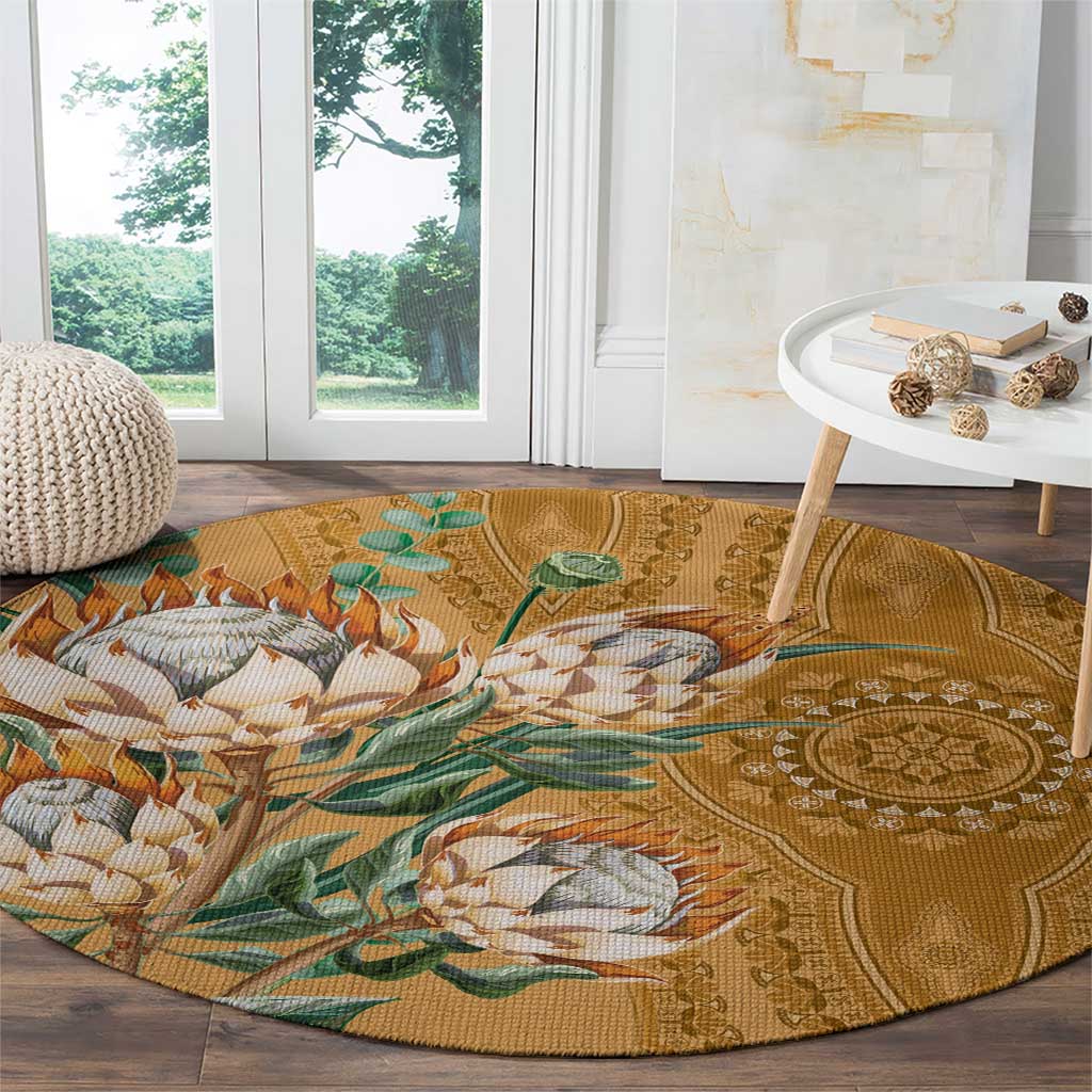 Round gold carpet with proteas, green leaves, and ornate medallion design on wood floor