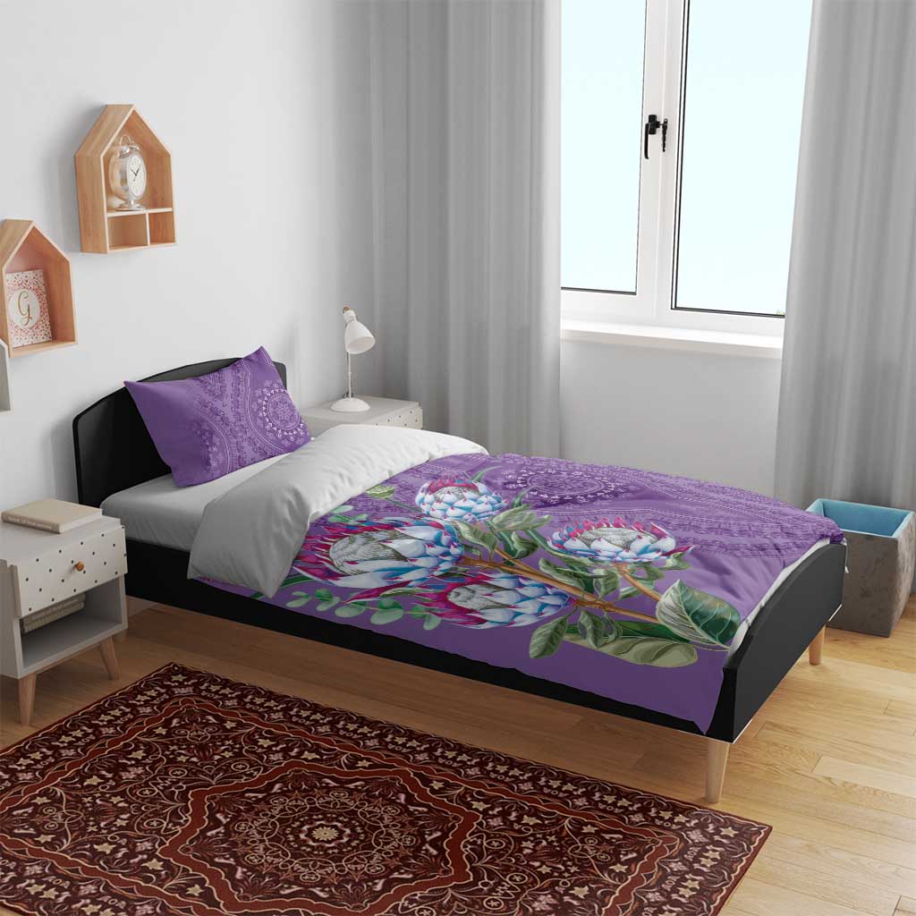 Violet bedding set with protea floral artwork and purple dashiki medallion accents, on bed