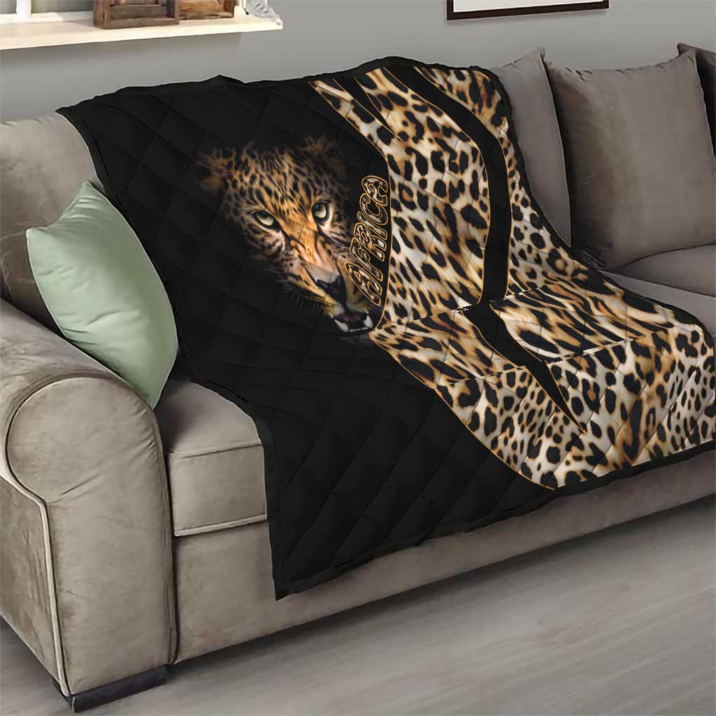 Black quilt blanket with leopard face and cream-brown spots, draped over a gray sofa