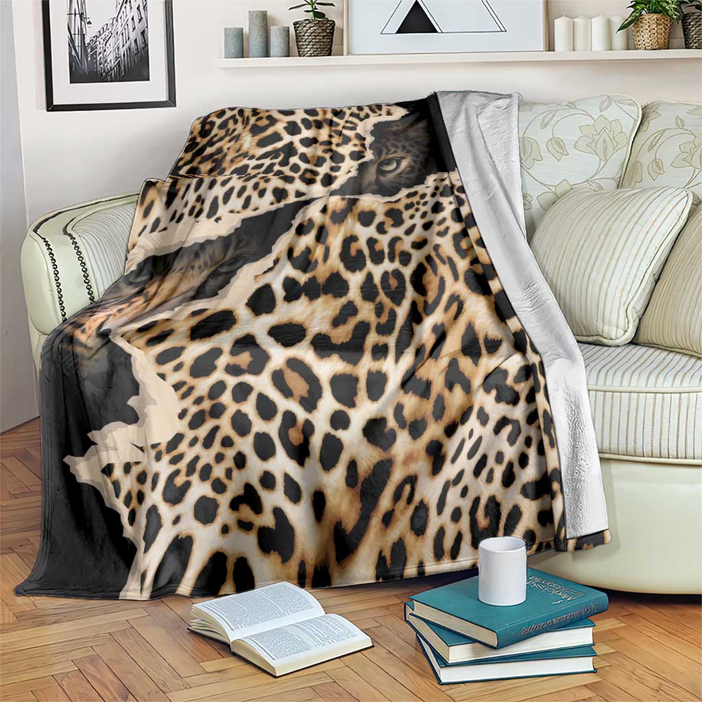 Black and tan leopard-print blanket with animal-face graphics, draped on a couch