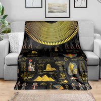 Black Egyptian hieroglyphs blanket draped on gray sofa with gold collar and figures