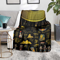 Black Egyptian hieroglyphs blanket on floor with gold collar trim and colorful scenes