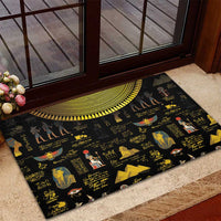 Black rubber doormat with Egyptian hieroglyphs and figures, yellow sun-disk arc near edge