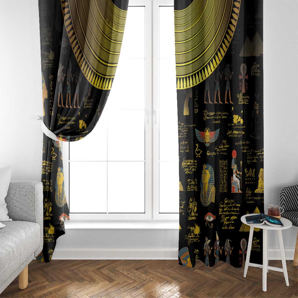 Black Egyptian window curtain with gold top valance and hieroglyph prints beside white door.