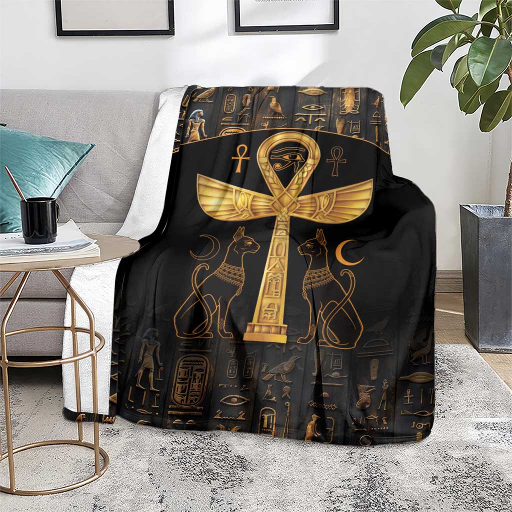 Black throw blanket with gold Ankh and Eye of Horus artwork, laid on chair