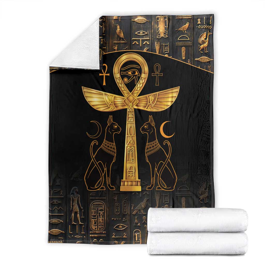 Black throw blanket with gold Ankh and Eye of Horus symbols, stacked with folded towels