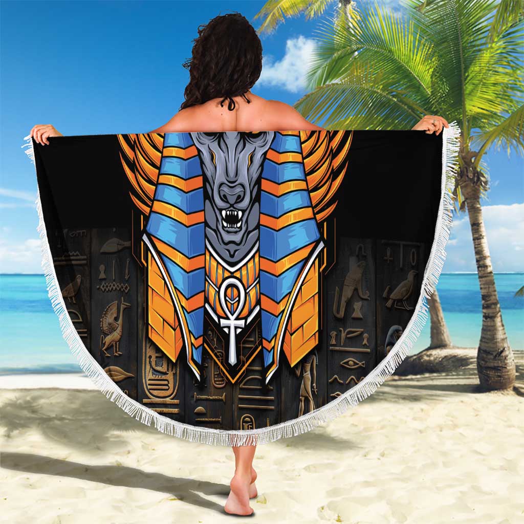Black round Anubis beach blanket with fringe edge held open on sandy beach