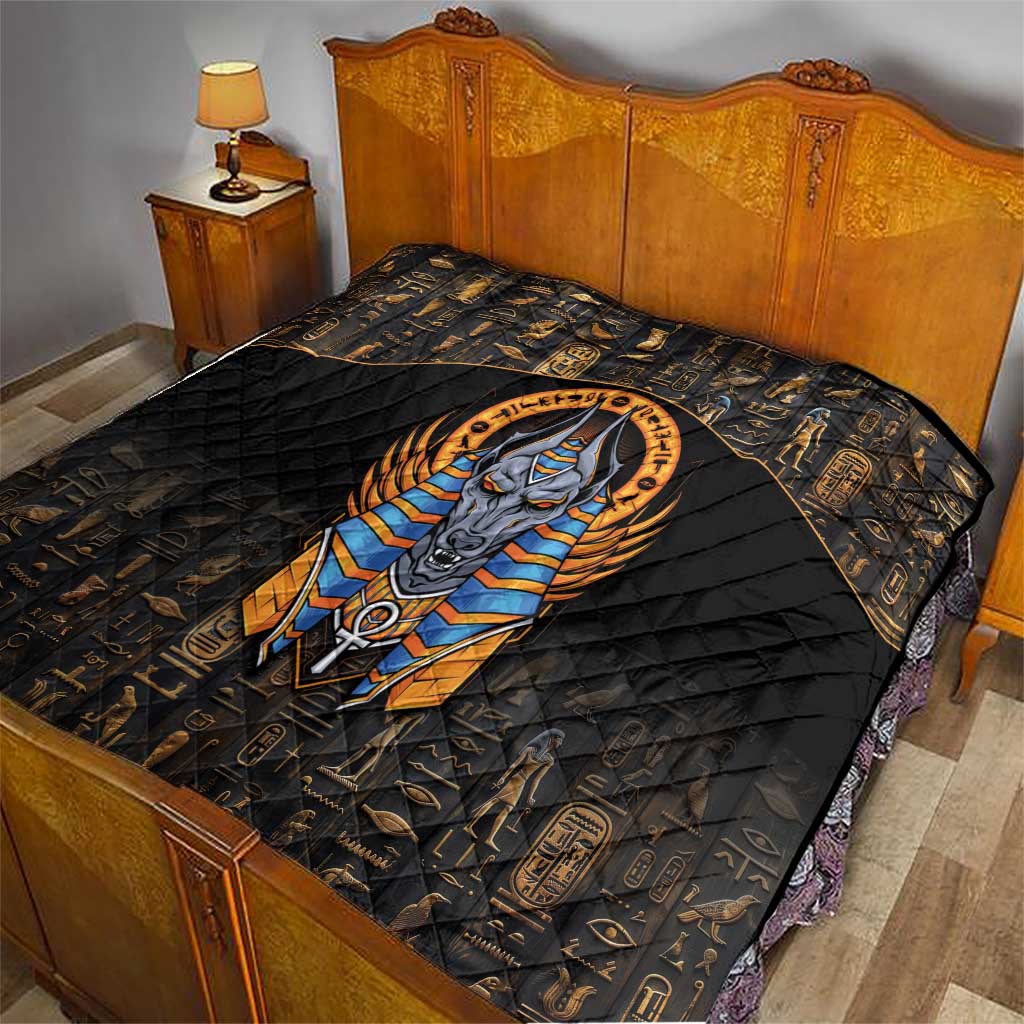 Black quilt on bed with gold Egyptian symbols and a large centered Anubis design