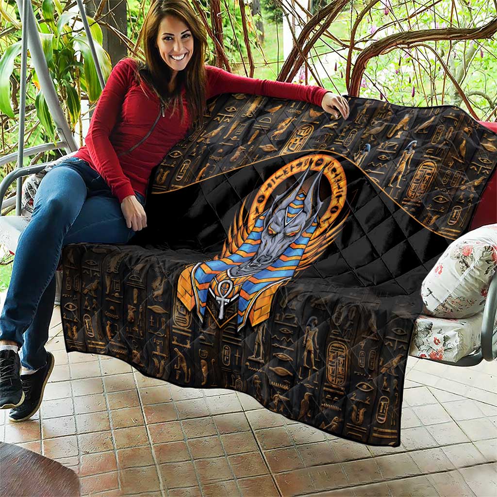 Black throw quilt with gold hieroglyphs, central Anubis portrait, and padded diamond look
