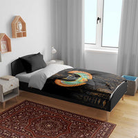 Black comforter with winged cat design and Egyptian glyphs, on a bed with dark pillows