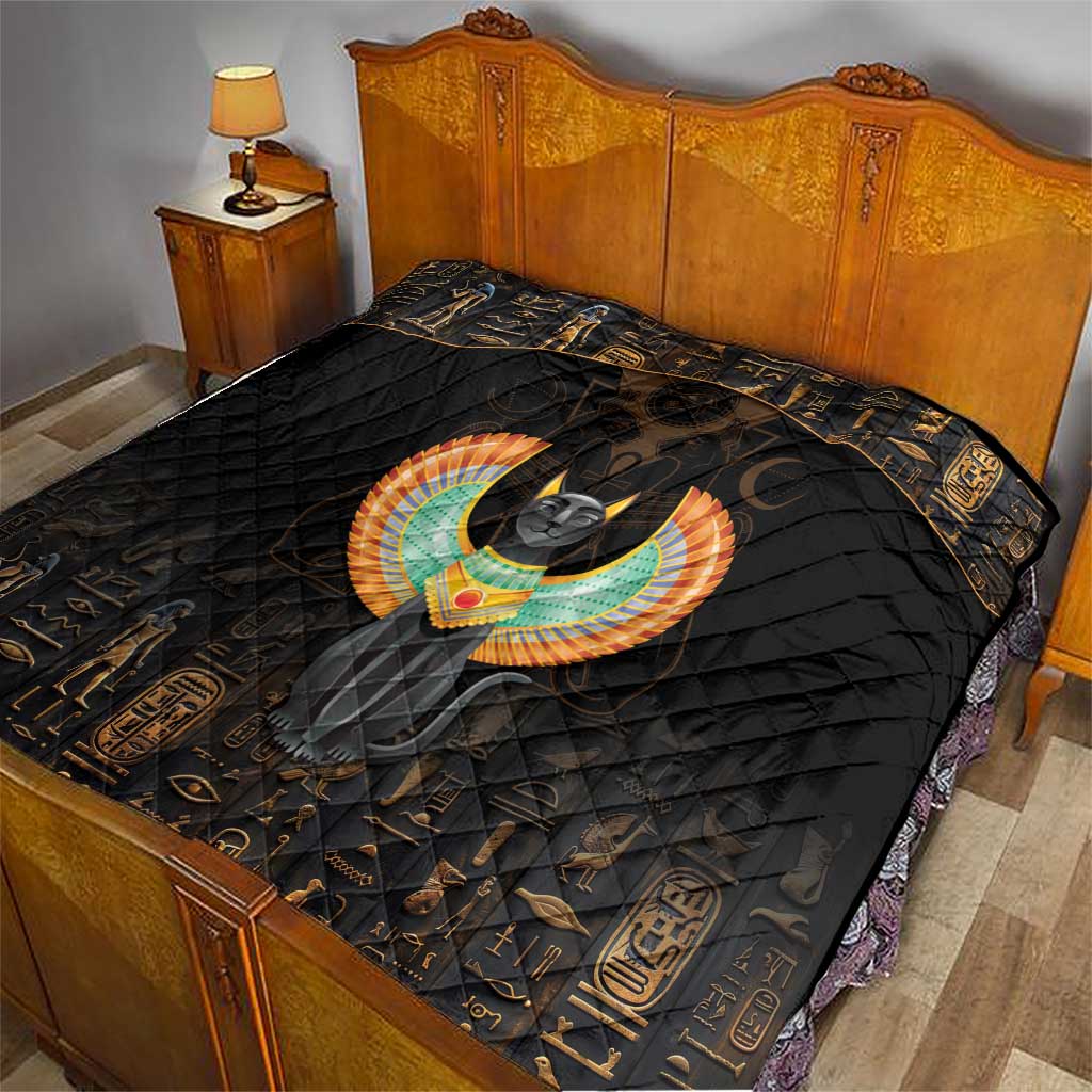 Black bed quilt with Egyptian cat and wings design, trimmed with gold hieroglyph-style icons