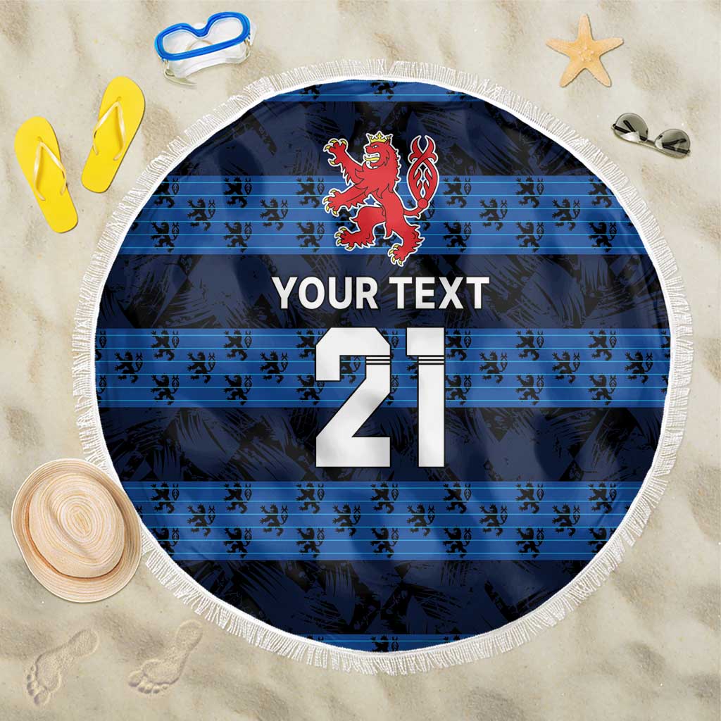 Blue round beach blanket with white fringe, red lion crest, '21' and 'YOUR TEXT'.