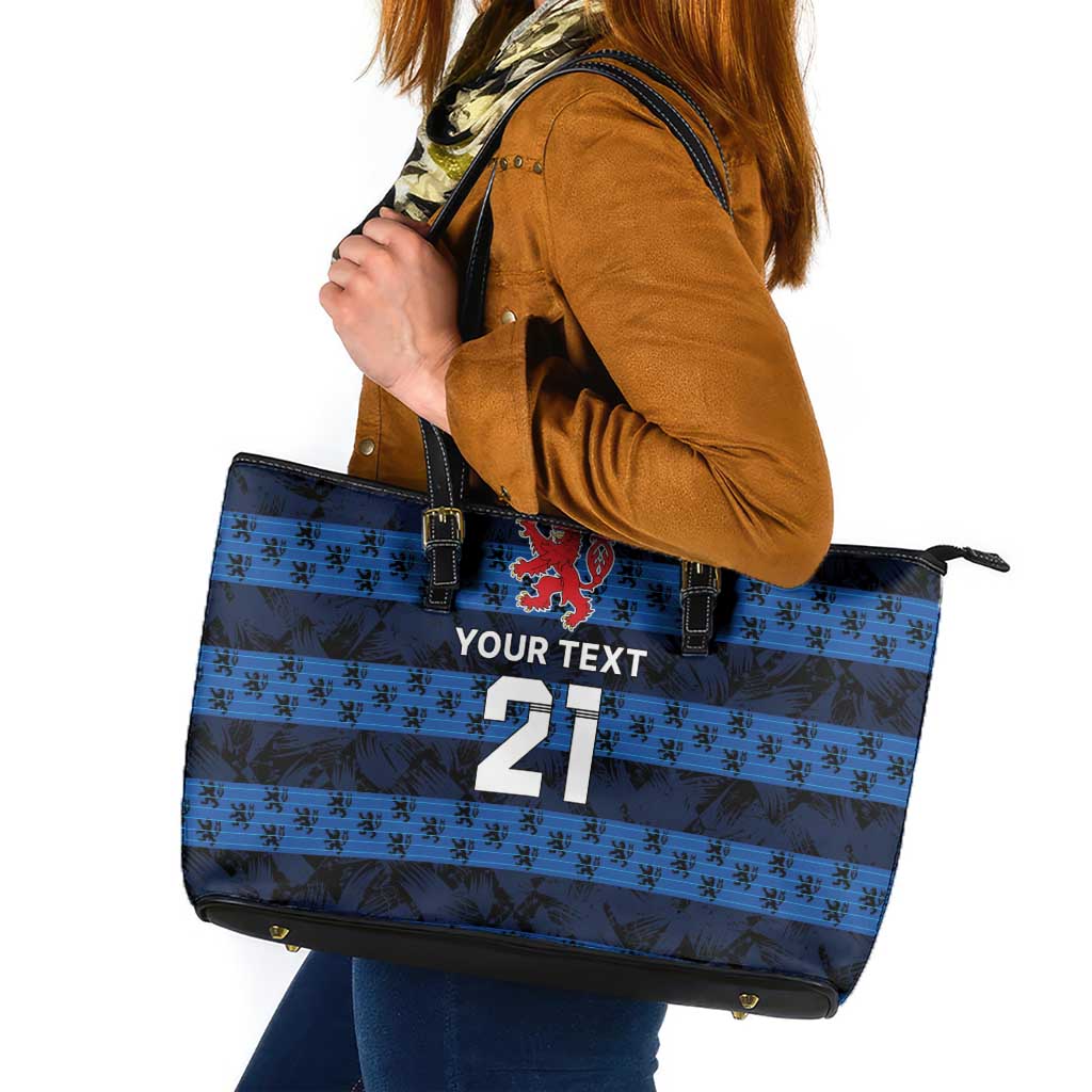 Blue tote bag with black leather handles, striped pattern, red crest and number 21