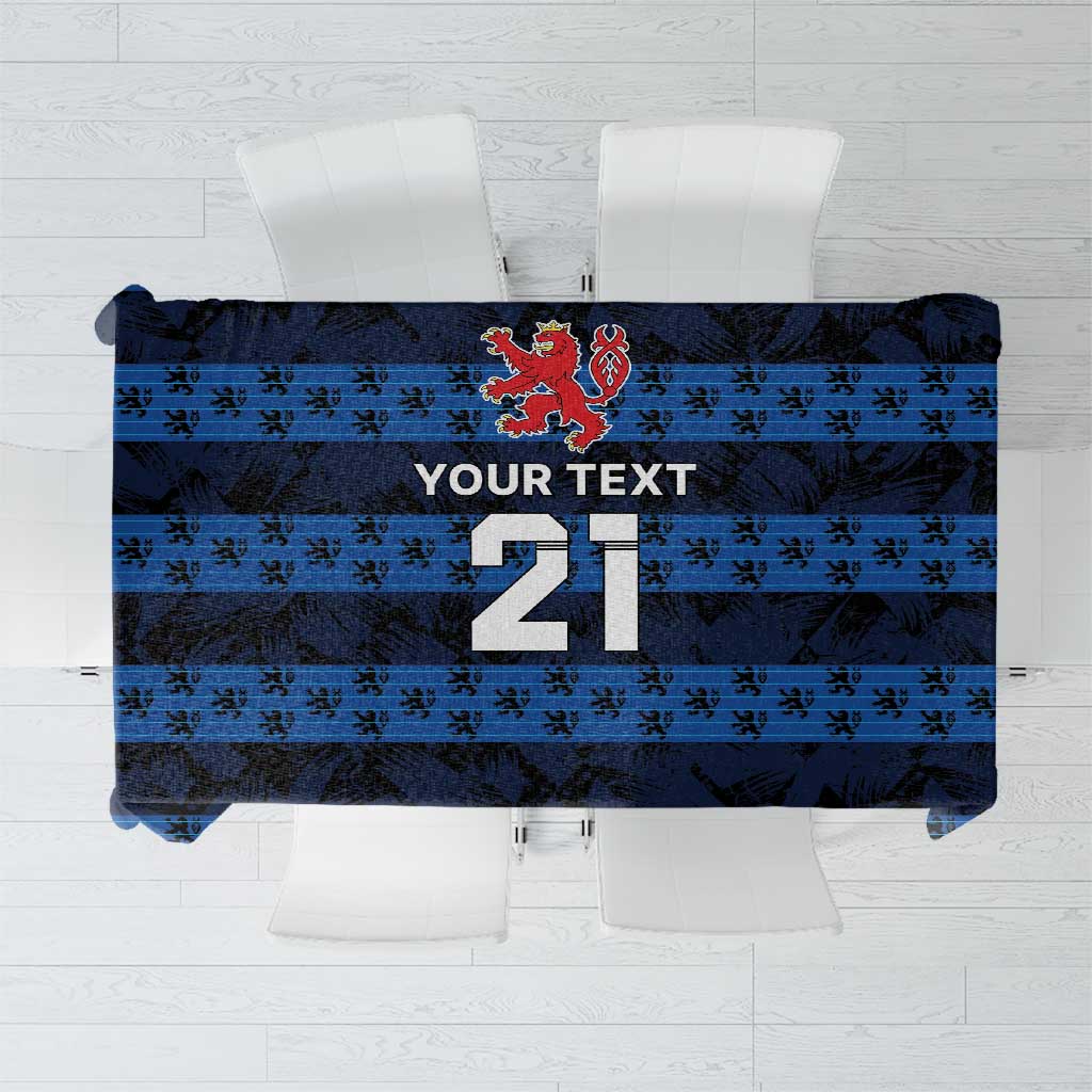 Blue tablecloth with dark repeating pattern, red crest, and large number design