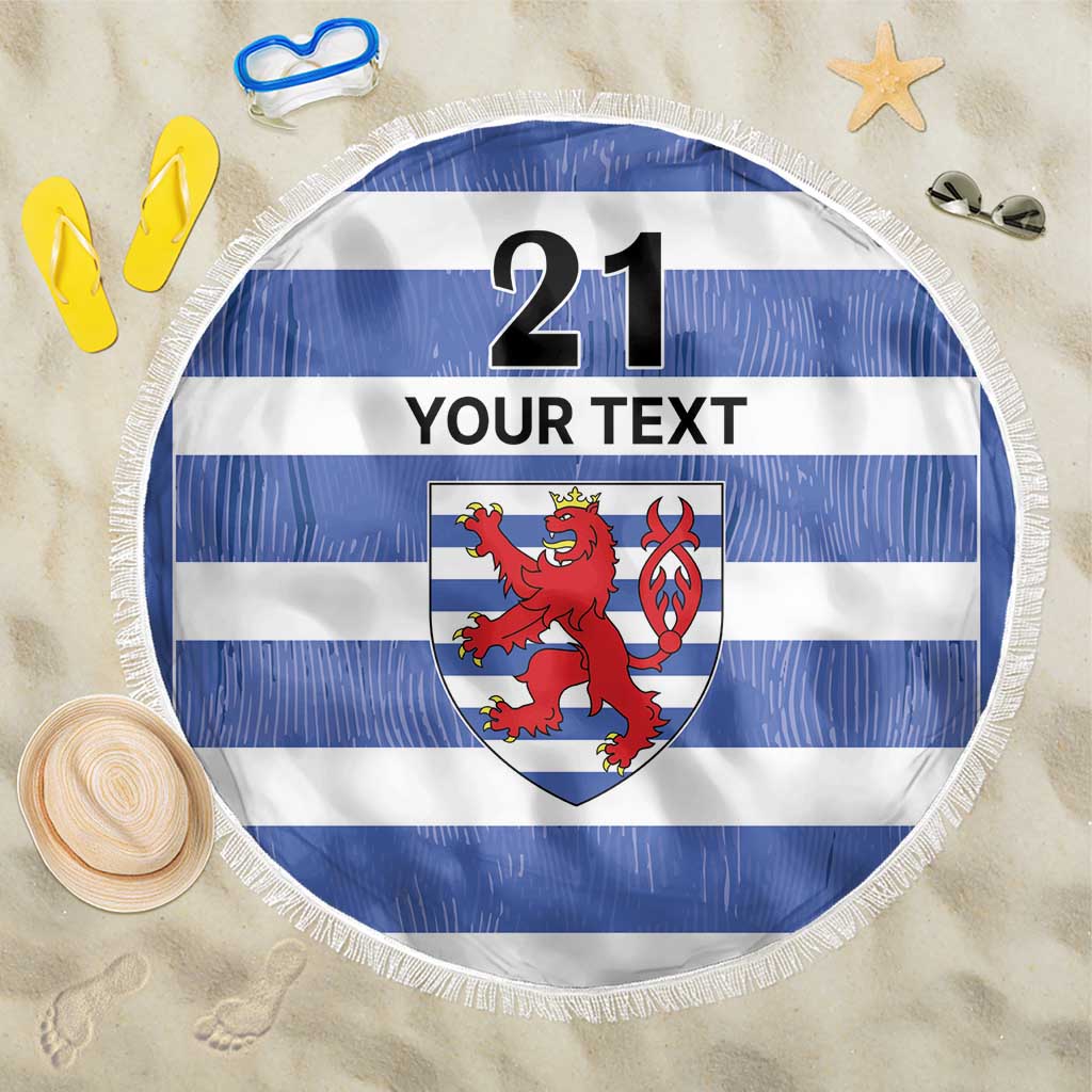 Round blue-and-white striped beach blanket with lion crest and fringed edge