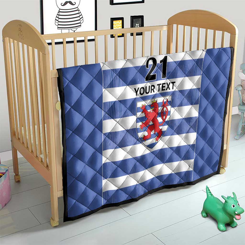 Blue quilt on a crib, with white stripes, number 21, custom text, and lion crest