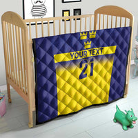 Blue and yellow Sweden-themed quilt in baby crib, crowns, 'YOUR TEXT' and 21