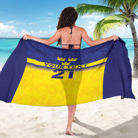 Blue custom sarong draped wide with crown logo, yellow panel, and number 21 at center.