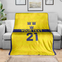 Gold custom rugby blanket draped on a sofa, navy stripe, crown symbols, 'YOUR TEXT' '21'