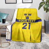 Gold rugby blanket on floor beside table, navy trim, crowns, 'YOUR TEXT' and large '21'