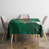 Green tablecloth on dining table with eagle emblem, floral details, and diagonal stripes.
