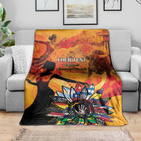 Personalized throw blanket draped on couch in gold and black with “Your Text” sunburst art