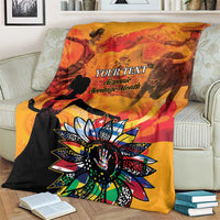 Personalized blanket on couch, gold orange and black design with “Your Text” and sunburst
