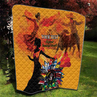 Gold quilt laid out showing red silhouettes, black dancer figure, and colorful flower centerpiece.