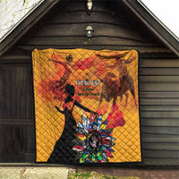 Gold quilt hanging on a wall with red silhouettes and colorful flower graphic, quilted look.