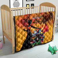 Gold quilt on a toddler bed with red dancer silhouettes and colorful flower emblem, quilted.