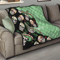 Green and black quilt draped over a sofa, showing sugar skulls with leaf and ribbon details