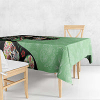 Green tablecloth draped over table with black sugar skull border design