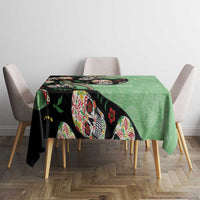 Green and black tablecloth featuring colorful sugar skull heads on tabletop