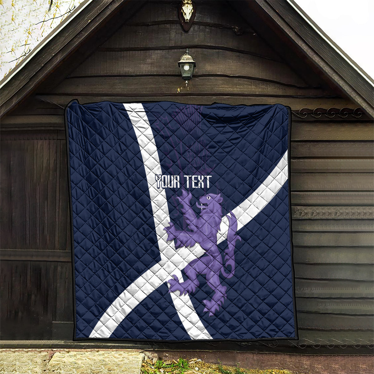 Navy quilt hung outdoors with white diagonal cross, purple lion graphic, “YOUR TEXT”