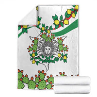 White blanket folded with cactus-and-lemon artwork and central woman face motif, stacked with roll.